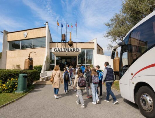 Groupe d’élèves accompagnés de leurs encadrants se dirigeant vers l’entrée de l’Usine-Musée de la Maison de Parfums Galimard à Grasse, après leur arrivée en car scolaire.