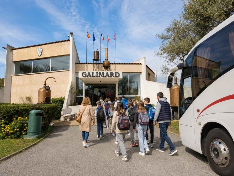 Groupe d’élèves accompagnés de leurs encadrants se dirigeant vers l’entrée de l’Usine-Musée de la Maison de Parfums Galimard à Grasse, après leur arrivée en car scolaire.